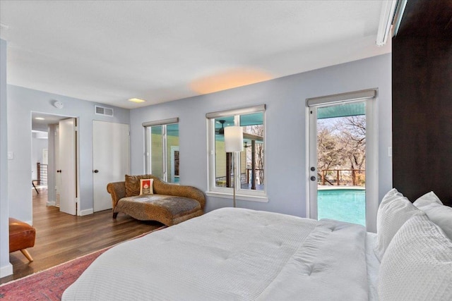 bedroom with visible vents, wood finished floors, and access to outside