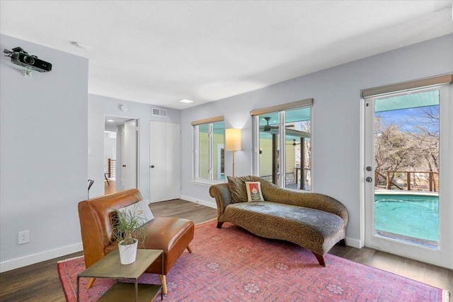 living area featuring a wealth of natural light, visible vents, baseboards, and wood finished floors