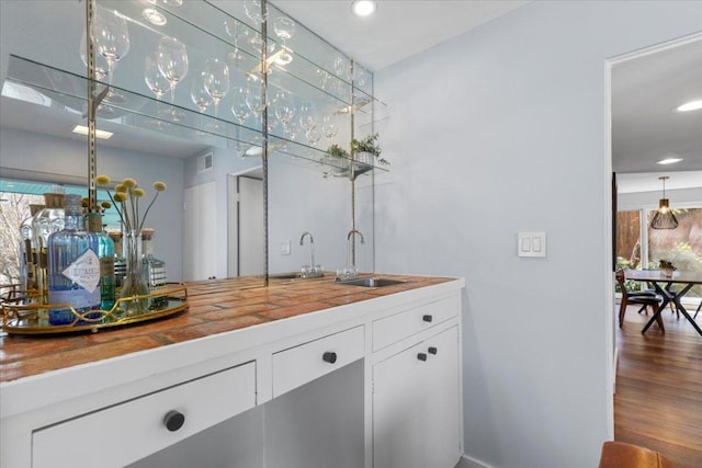 bar with a sink, wet bar, wood finished floors, and recessed lighting