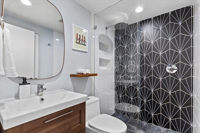 bathroom featuring a tile shower, toilet, and vanity