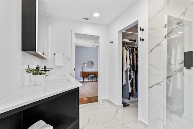 full bath with visible vents, a walk in closet, marble finish floor, recessed lighting, and vanity