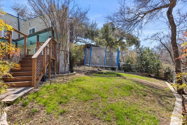 view of yard with stairway, a trampoline, and ceiling fan