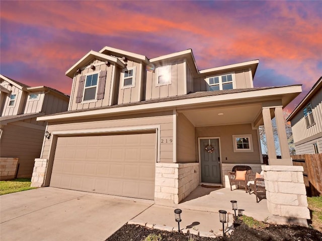 view of front of house with driveway, fence, covered porch, board and batten siding, and a garage