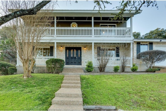 view of property with stone siding, a balcony, a porch, and a front yard