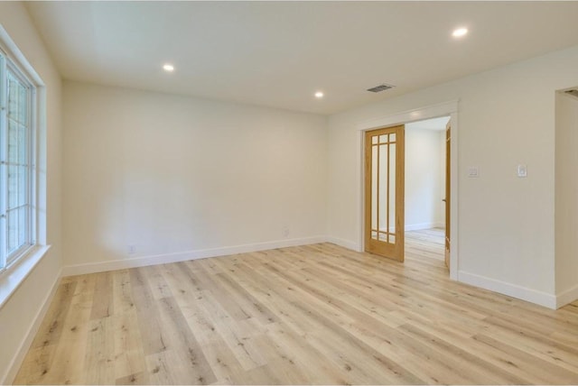 empty room featuring light wood finished floors, visible vents, recessed lighting, and baseboards