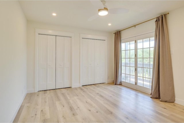 unfurnished bedroom with baseboards, multiple closets, wood finished floors, and access to exterior