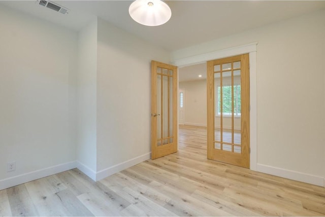 empty room featuring visible vents, baseboards, and wood finished floors