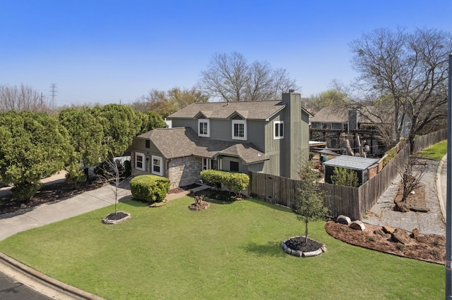 view of front of house featuring a chimney, a shingled roof, a front yard, and fence