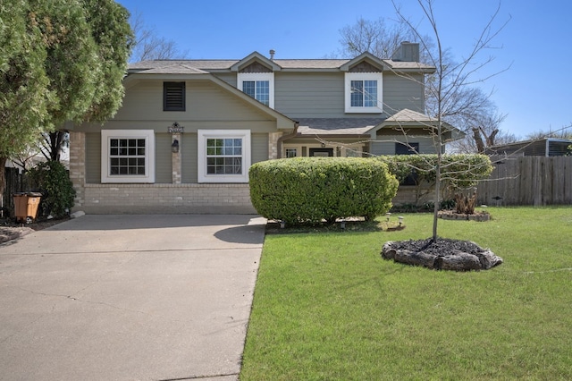 traditional-style home with a front yard, fence, driveway, a chimney, and brick siding