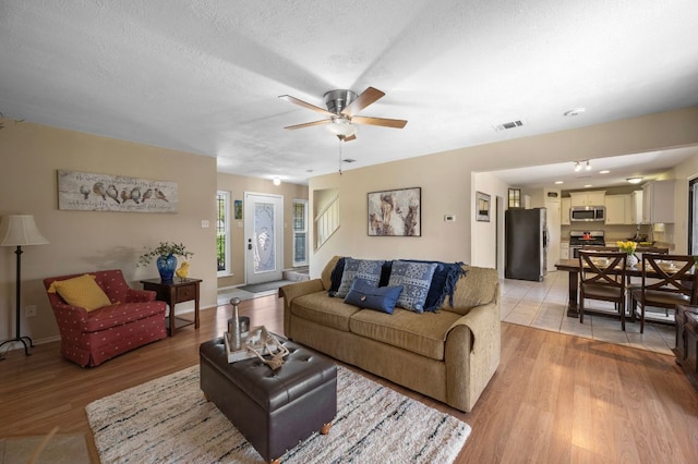 1807 Morning Quail Dr, Austin, TX 78758 - living area with light wood-type flooring, ceiling fan, a textured ceiling, and baseboards