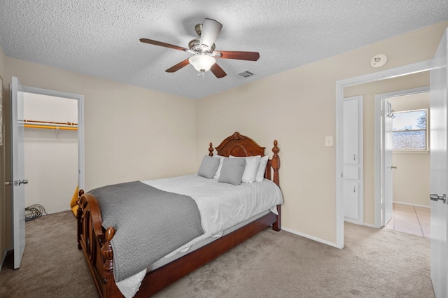 1807 Morning Quail Dr, Austin, TX 78758 - bedroom with light colored carpet, a textured ceiling, a ceiling fan, a closet, and a walk in closet