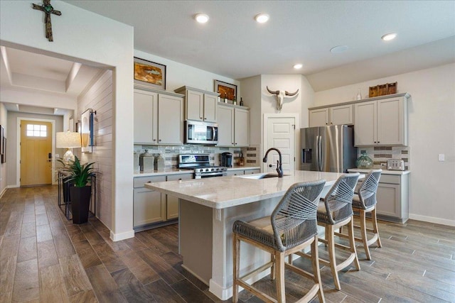 kitchen featuring a sink, stainless steel appliances, a kitchen bar, and dark wood-style floors