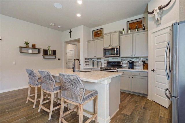 kitchen with tasteful backsplash, wood tiled floor, gray cabinets, appliances with stainless steel finishes, and a sink