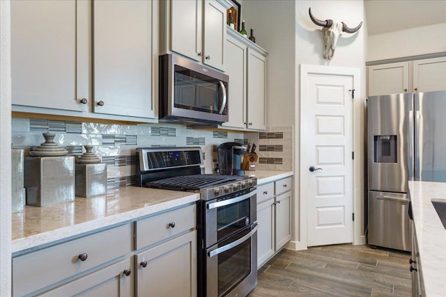 7708 Skytree Dr, Austin, TX 78744 - kitchen featuring stainless steel appliances, backsplash, dark wood-style floors, light stone counters, and gray cabinets