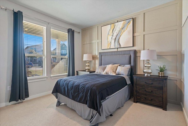 bedroom featuring baseboards, light carpet, and a decorative wall