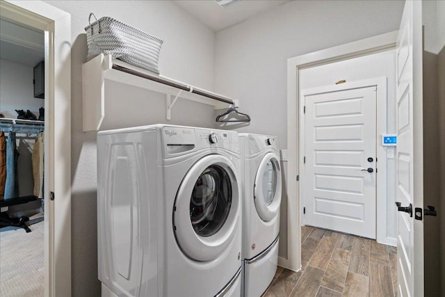 clothes washing area with washing machine and clothes dryer, laundry area, and wood finish floors