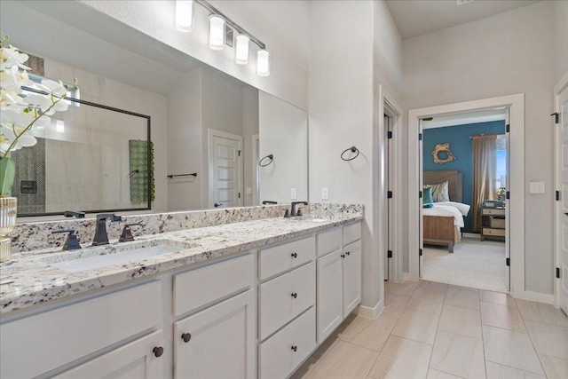 ensuite bathroom featuring double vanity, a shower stall, ensuite bath, and a sink