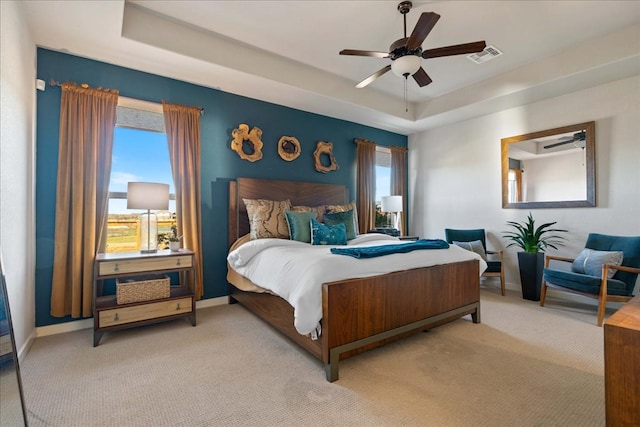 bedroom with a raised ceiling, carpet flooring, baseboards, and visible vents