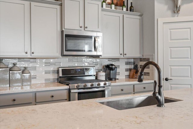 7708 Skytree Dr, Austin, TX 78744 - kitchen featuring stainless steel appliances, a sink, gray cabinetry, and backsplash