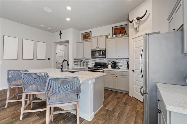 kitchen featuring tasteful backsplash, a sink, gray cabinets, appliances with stainless steel finishes, and dark wood-style flooring