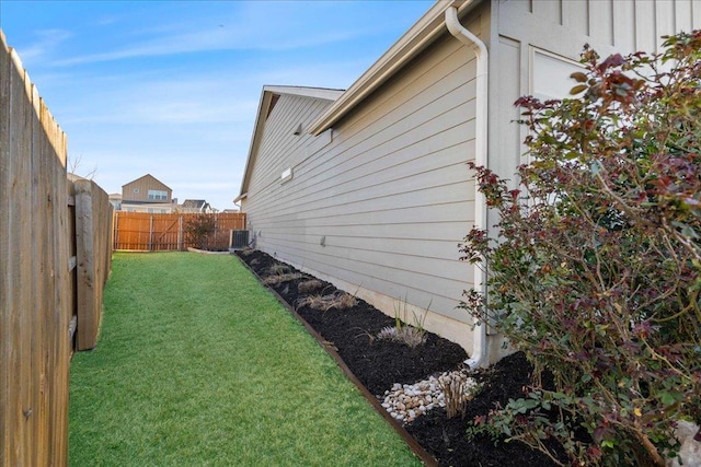 view of property exterior featuring central AC unit, a lawn, and a fenced backyard