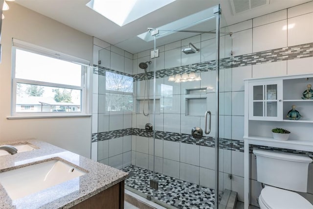 full bath featuring visible vents, toilet, a skylight, and a shower stall