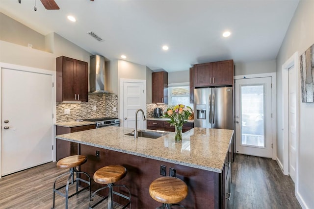 6519 Pevensey Dr, Austin, TX 78745 - kitchen featuring wall chimney range hood, stainless steel appliances, vaulted ceiling, dark wood-type flooring, and a breakfast bar