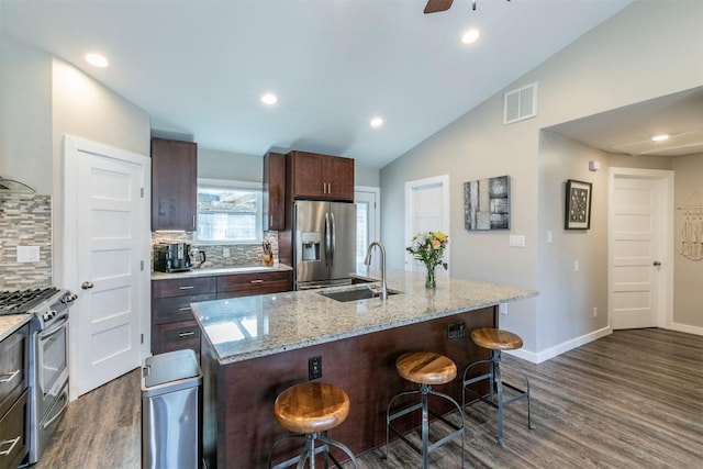 kitchen with a breakfast bar area, dark wood-style flooring, a sink, visible vents, and appliances with stainless steel finishes