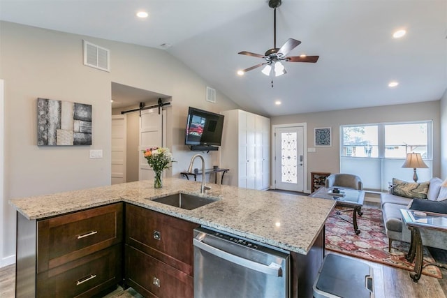 kitchen featuring visible vents, open floor plan, dishwasher, a barn door, and a sink