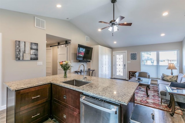 kitchen with a sink, a barn door, stainless steel dishwasher, open floor plan, and visible vents