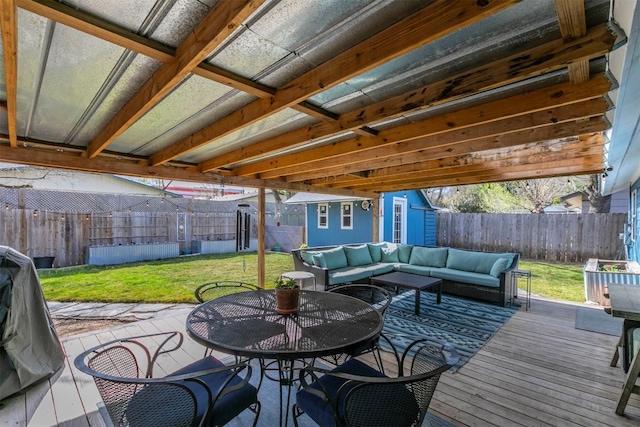 wooden deck with an outdoor living space, a lawn, outdoor dining area, a fenced backyard, and an outbuilding