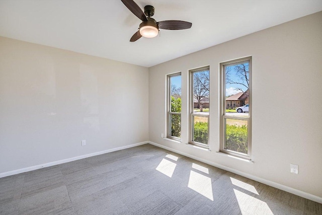 spare room with carpet, a ceiling fan, and baseboards