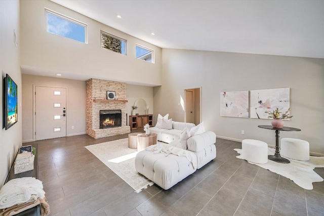 living room with recessed lighting, baseboards, a high ceiling, and a stone fireplace