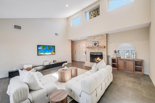 living area with visible vents, baseboards, a towering ceiling, and a fireplace