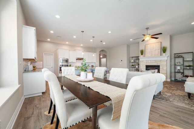 dining area with recessed lighting, a ceiling fan, arched walkways, and light wood finished floors