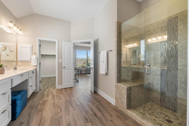 full bath featuring vaulted ceiling, a shower stall, vanity, and wood finished floors