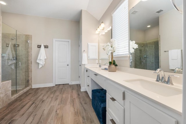 full bathroom featuring a sink, visible vents, wood finished floors, and a shower stall