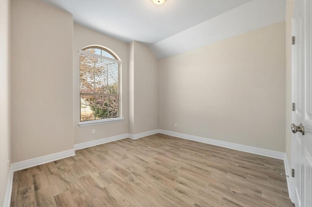 unfurnished room featuring baseboards, lofted ceiling, and light wood finished floors