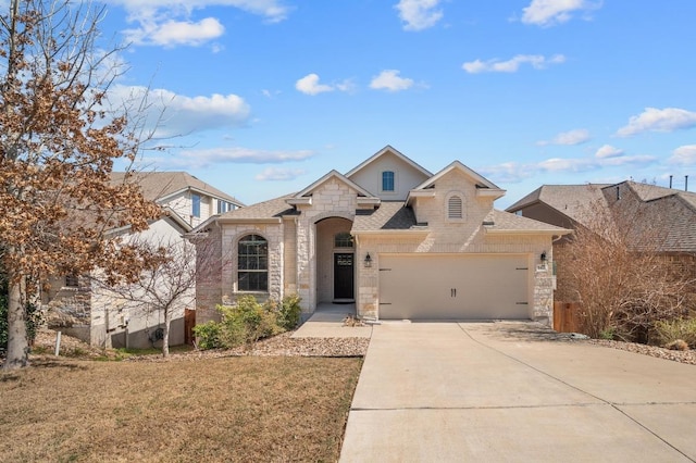 french provincial home with stone siding, driveway, an attached garage, and a shingled roof