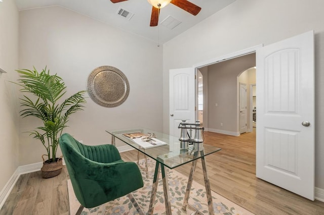 home office featuring arched walkways, visible vents, light wood-style flooring, and ceiling fan