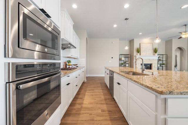 kitchen with light wood-style flooring, a sink, stainless steel appliances, white cabinets, and backsplash