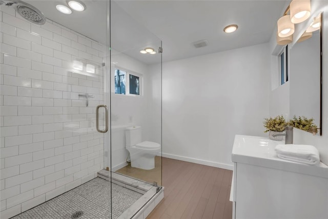 full bath with toilet, a stall shower, wood finished floors, baseboards, and vanity