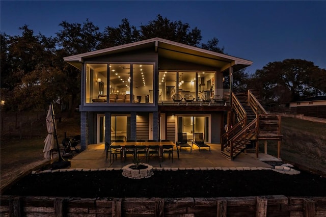 back of house at night featuring stairway, a patio, and an outdoor fire pit