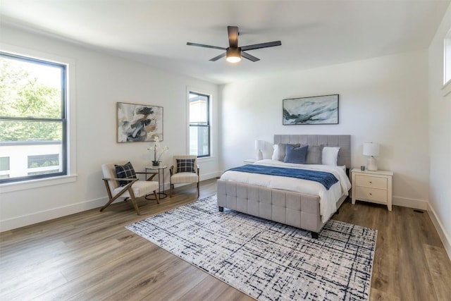 bedroom featuring baseboards, multiple windows, and wood finished floors