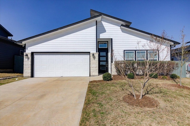 mid-century modern home with an attached garage, stone siding, and driveway