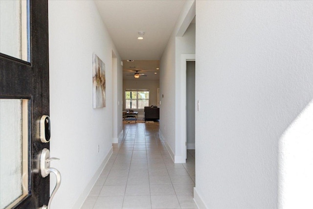 hallway featuring light tile patterned floors and baseboards