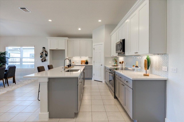 kitchen featuring light tile patterned floors, gray cabinetry, stainless steel appliances, and a sink