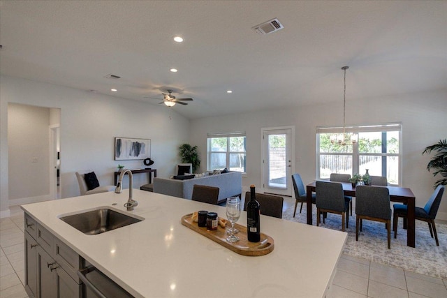 kitchen with visible vents, lofted ceiling, ceiling fan with notable chandelier, light tile patterned flooring, and a sink