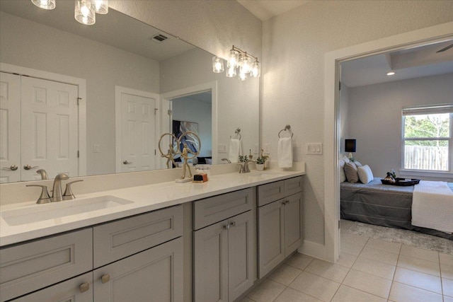 ensuite bathroom featuring tile patterned flooring, connected bathroom, visible vents, and a sink