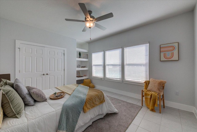 bedroom featuring a ceiling fan, light tile patterned floors, baseboards, and a closet